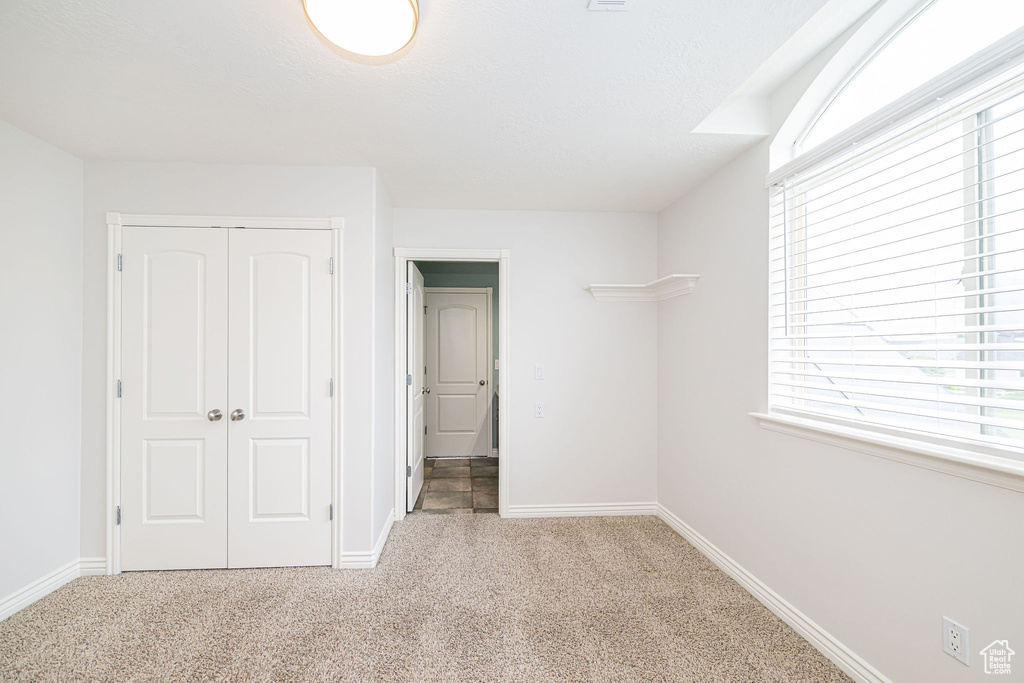 Unfurnished bedroom featuring carpet flooring, a closet, and baseboards