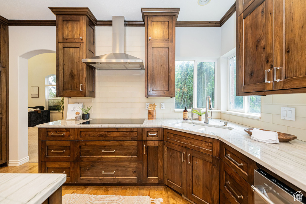 Kitchen featuring a sink, crown molding, stainless steel dishwasher, backsplash, and light wood finished floors
