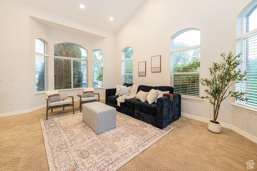 Carpeted living area featuring high vaulted ceiling, recessed lighting, and baseboards