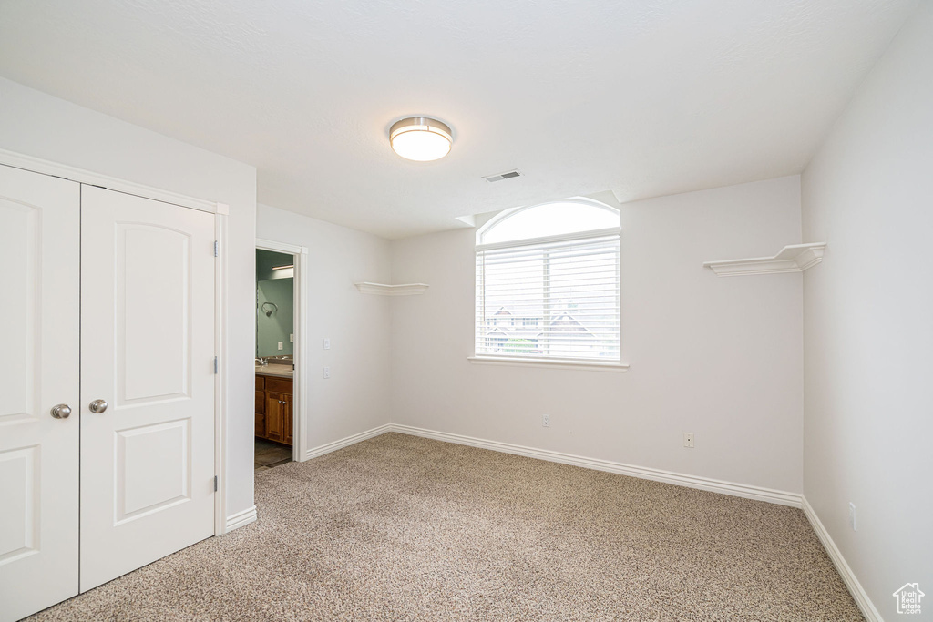 Unfurnished bedroom with light carpet, baseboards, and a closet