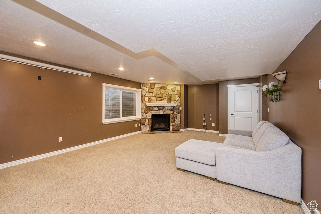 Living area with baseboards, carpet floors, a textured ceiling, a stone fireplace, and recessed lighting