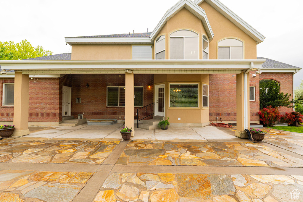 View of front of house featuring brick siding, roof with shingles, stucco siding, and entry steps