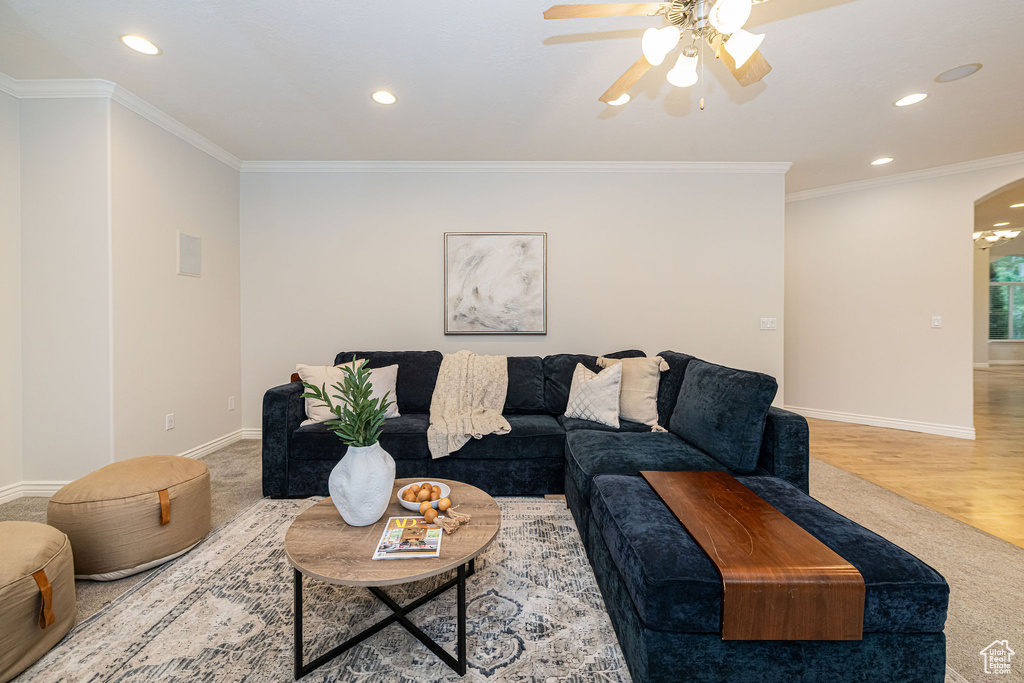 Carpeted living room featuring recessed lighting, ceiling fan, baseboards, arched walkways, and ornamental molding