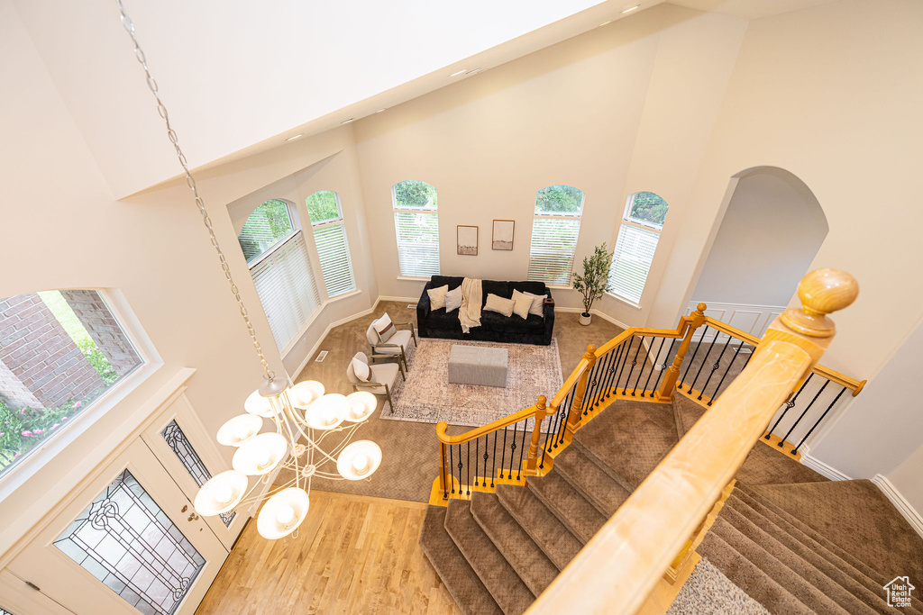 Living room with a high ceiling, healthy amount of natural light, baseboards, wood finished floors, and stairway