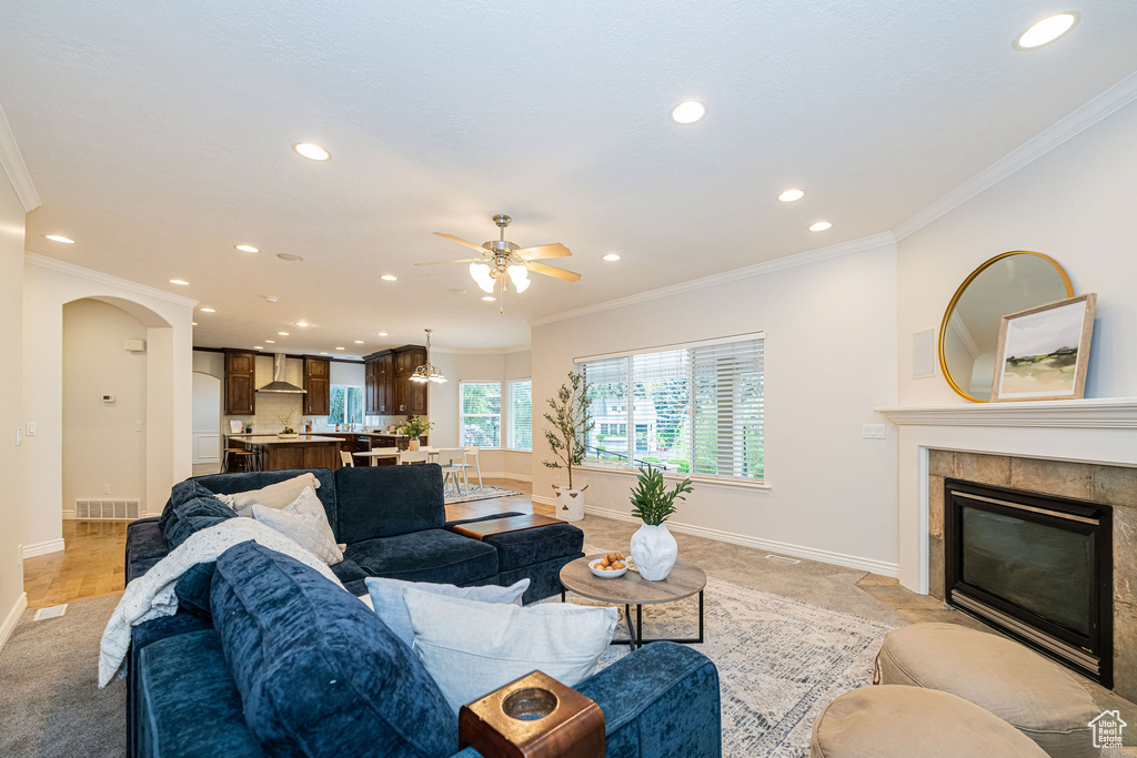 Living room featuring recessed lighting, crown molding, ceiling fan, baseboards, and a tile fireplace