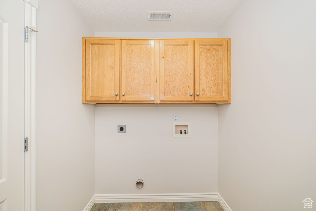 Washroom with electric dryer hookup, washer hookup, cabinet space, and baseboards