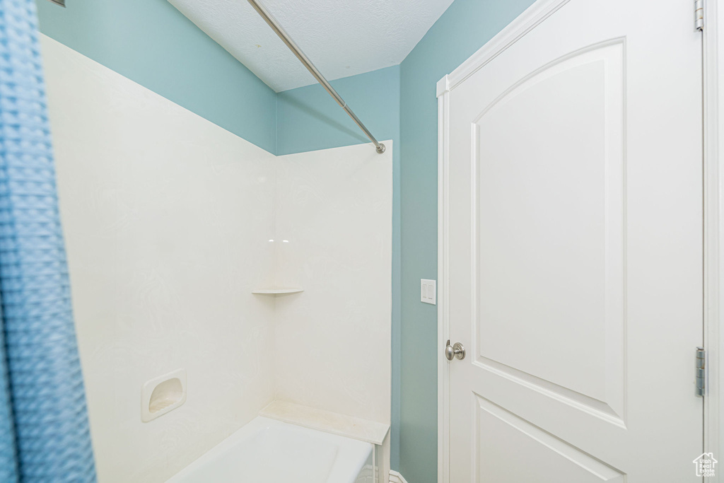 Full bath with a textured ceiling and washtub / shower combination