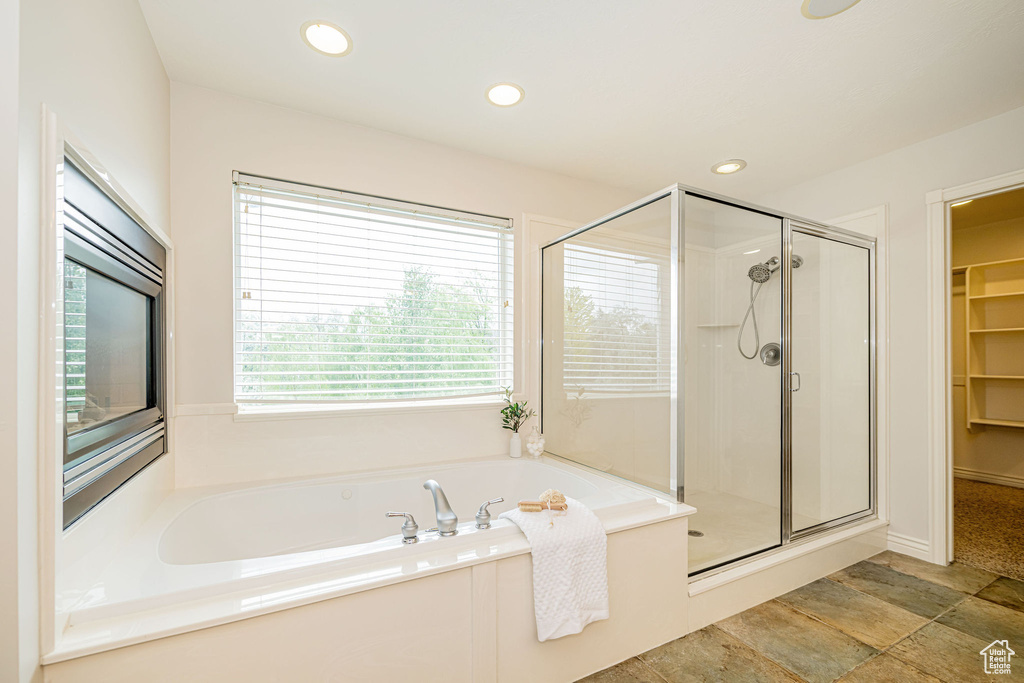 Bathroom featuring a shower stall, a bath, a spacious closet, recessed lighting, and stone finish floors