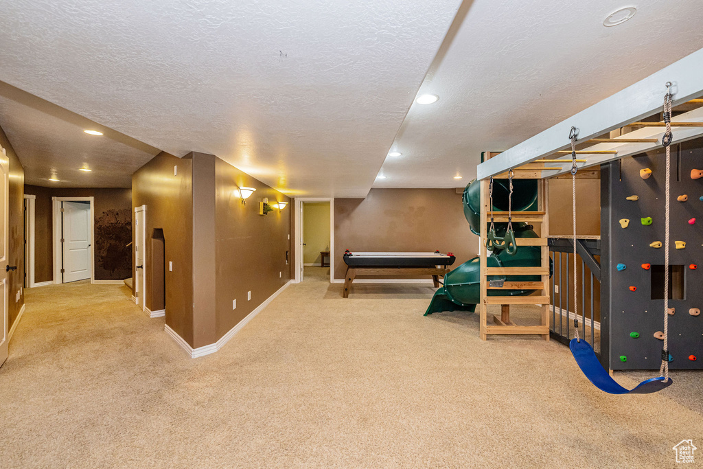 Finished below grade area featuring carpet flooring, baseboards, a textured ceiling, and recessed lighting