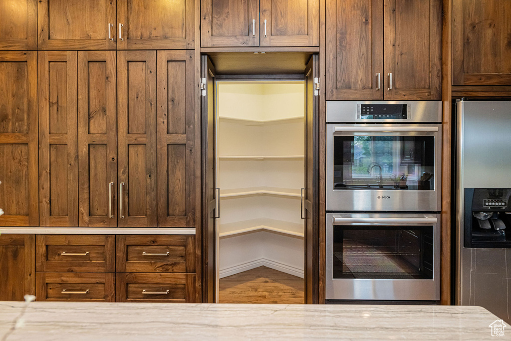 Kitchen featuring appliances with stainless steel finishes, light stone counters, and wood finished floors