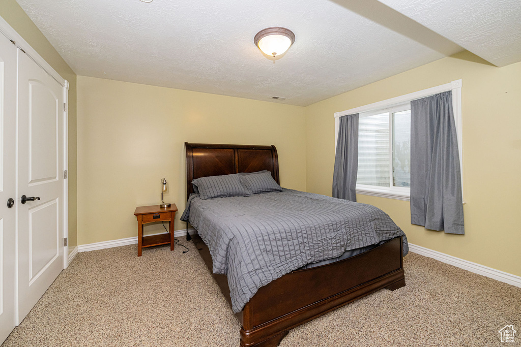 Bedroom with carpet floors, baseboards, and a textured ceiling