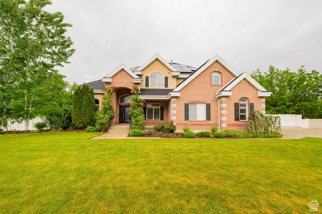 Traditional-style home featuring brick siding, roof mounted solar panels, and stucco siding