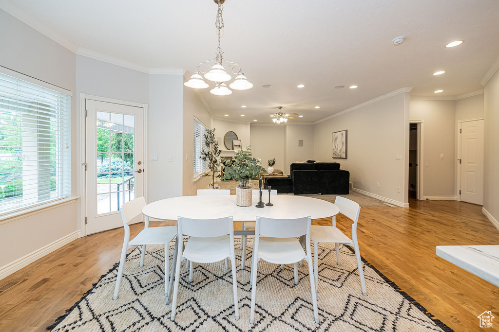 Dining space with ornamental molding, light wood finished floors, recessed lighting, baseboards, and a chandelier