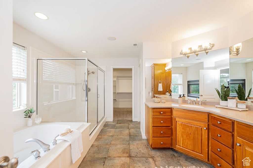 Bathroom featuring vanity, a stall shower, a bath, baseboards, and recessed lighting