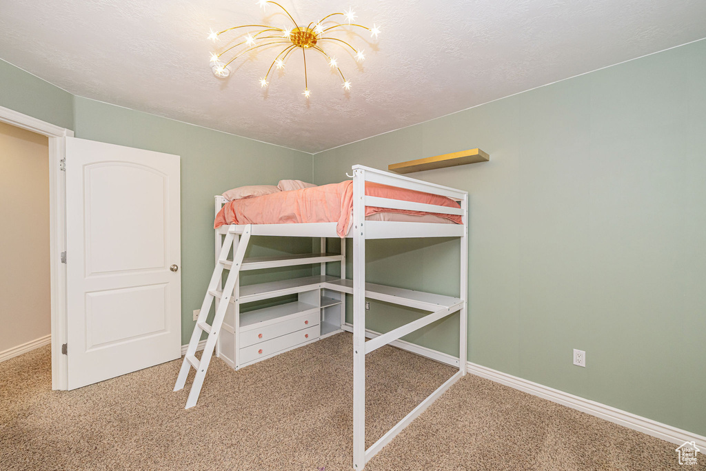 Bedroom with carpet floors, a chandelier, baseboards, and a textured ceiling