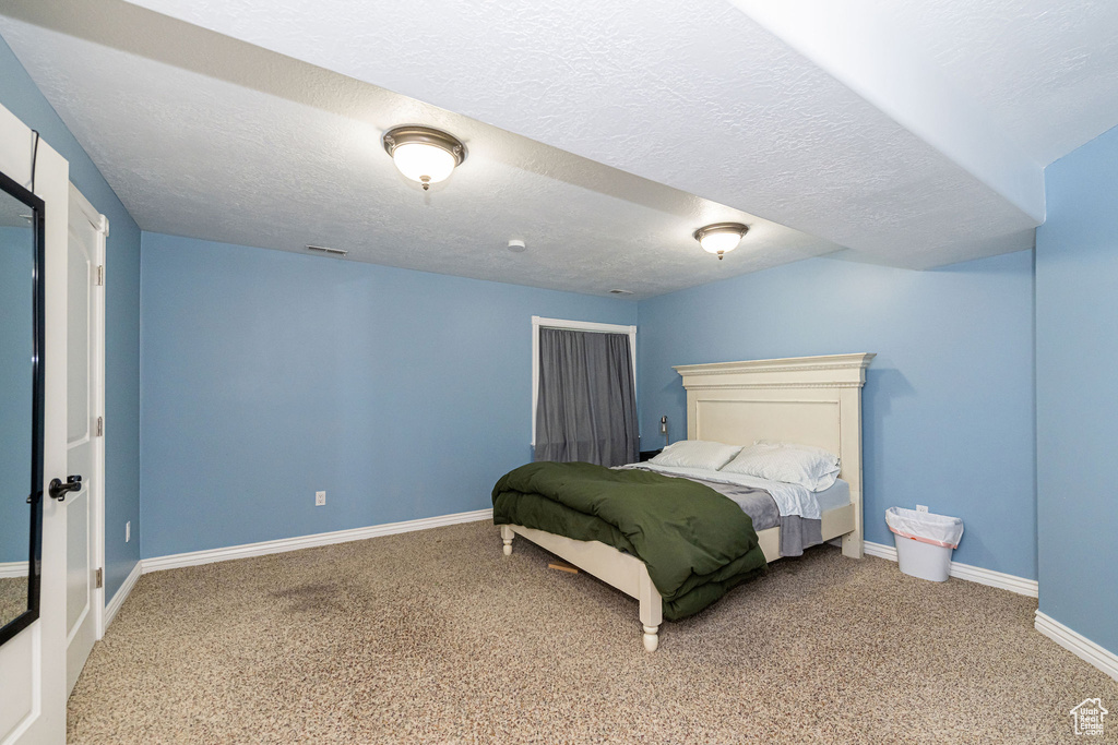 Bedroom with carpet flooring, baseboards, and a textured ceiling
