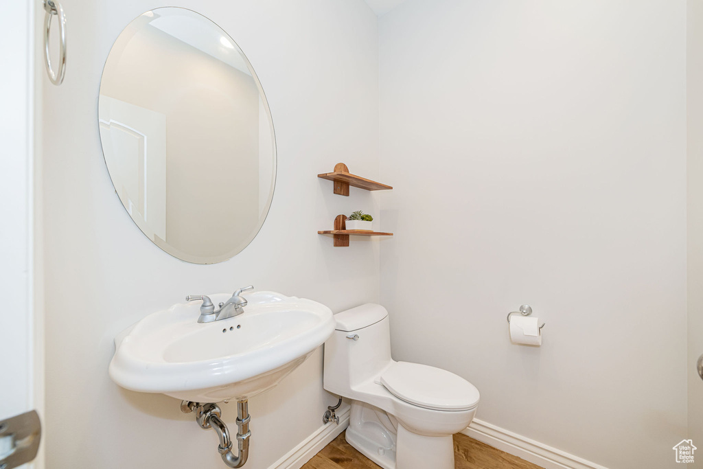 Half bathroom with wood finished floors, toilet, and baseboards
