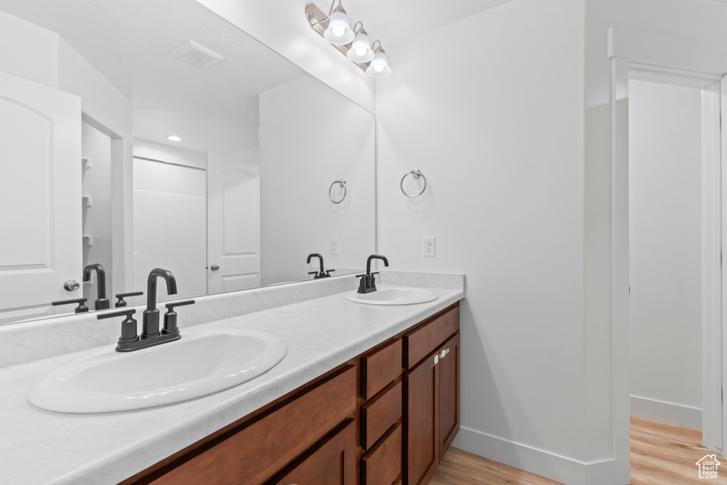Bathroom with wood finished floors, double vanity, and baseboards