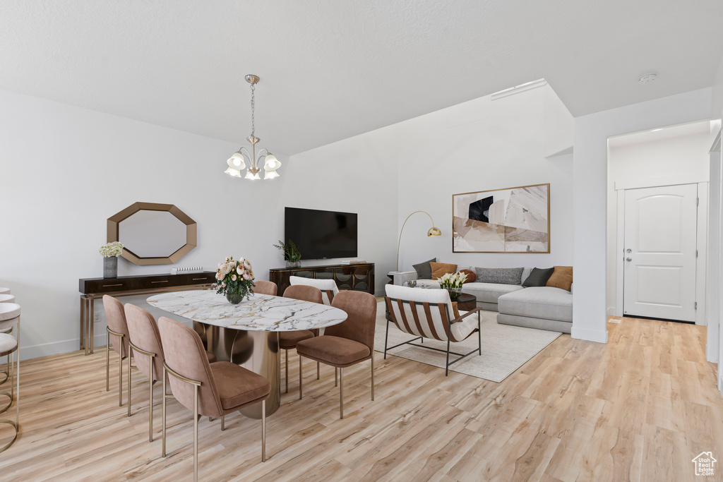 Dining area featuring light wood-style flooring, a chandelier, baseboards, and lofted ceiling