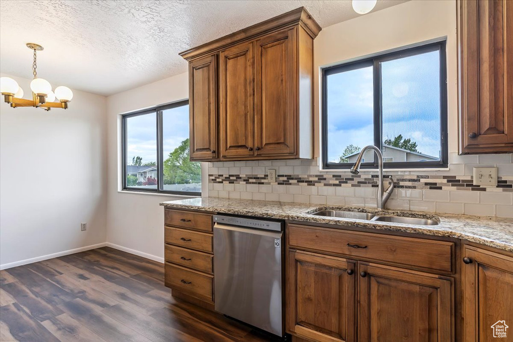 Kitchen featuring stainless steel dishwasher, a sink, dark wood-style floors, backsplash, and brown cabinetry