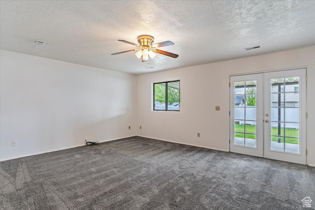 Carpeted empty room featuring french doors, ceiling fan, and a textured ceiling