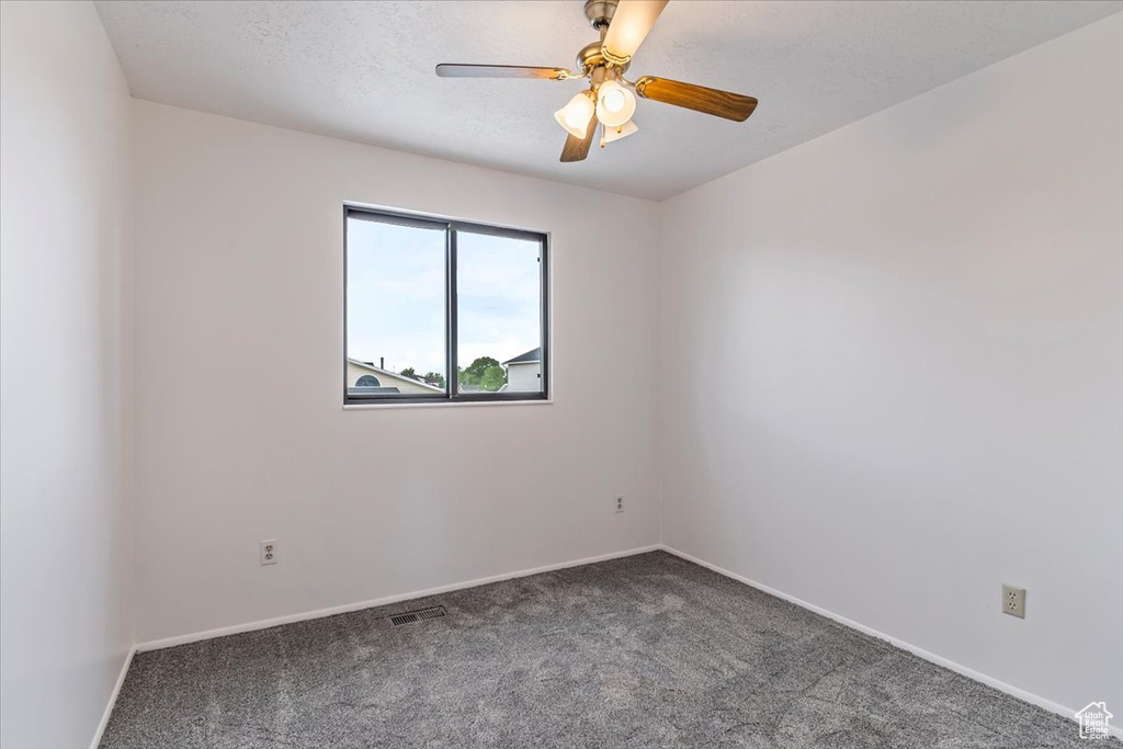 Carpeted empty room featuring a ceiling fan and baseboards