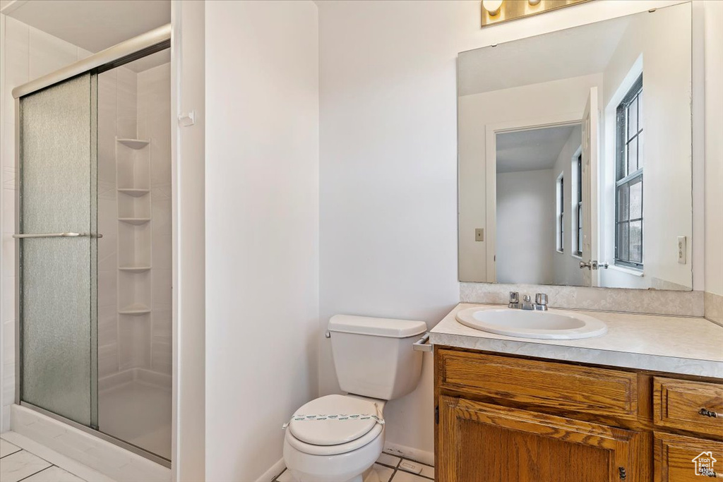 Bathroom with a shower stall, toilet, tile patterned floors, vanity, and baseboards