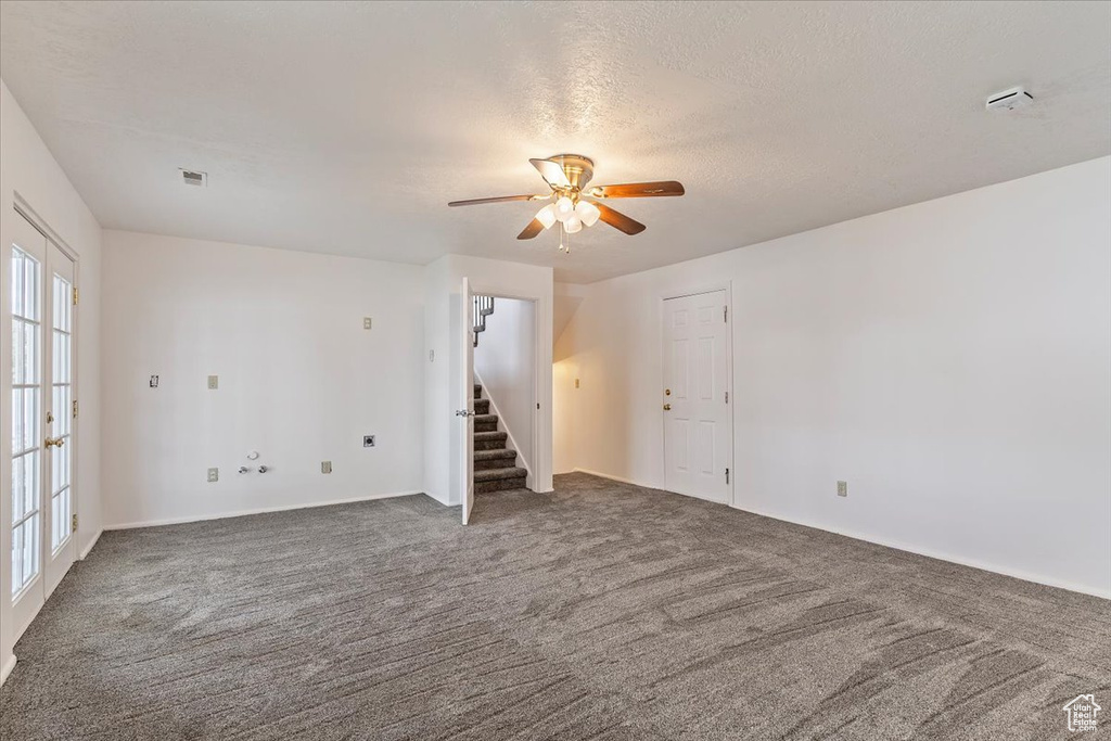 Carpeted spare room with ceiling fan, stairway, a textured ceiling, and baseboards