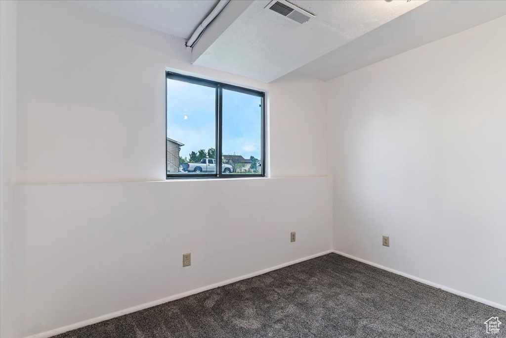 Spare room with dark carpet and baseboards