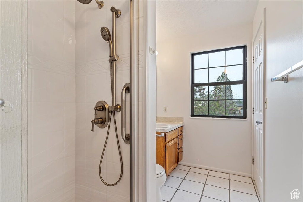 Full bath with tiled shower, vanity, tile patterned flooring, and toilet
