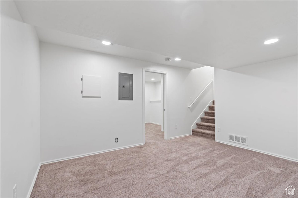 Finished basement with carpet, stairs, recessed lighting, electric panel, and baseboards