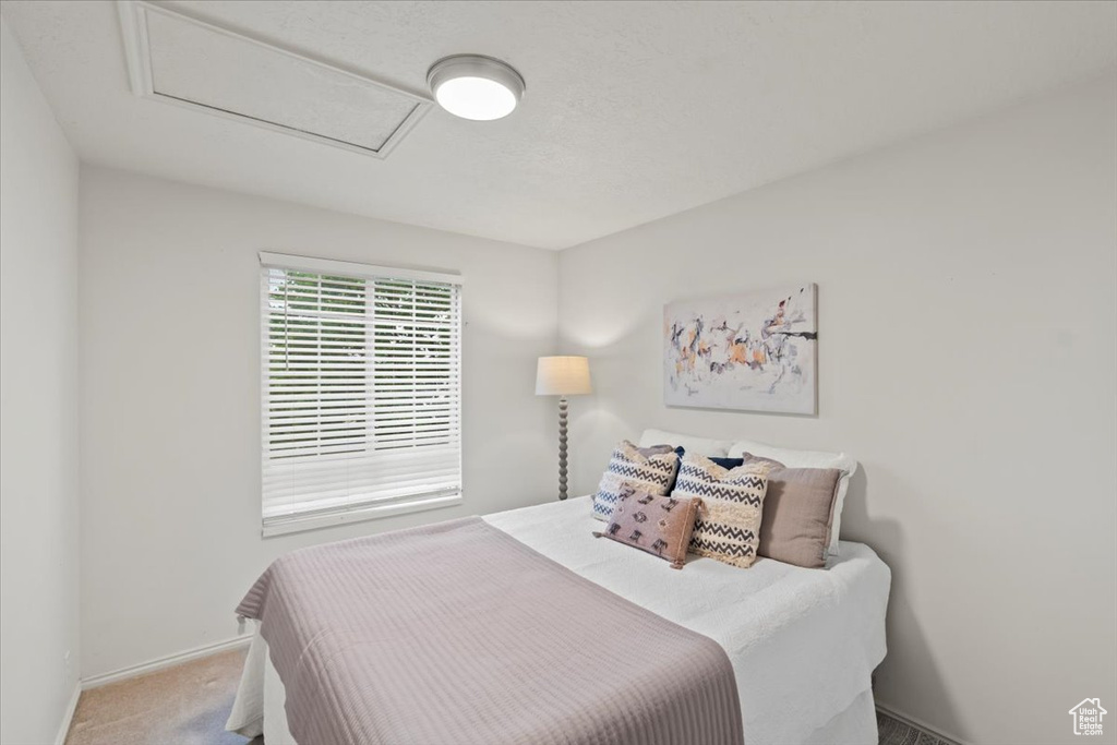 Carpeted bedroom featuring attic access and baseboards