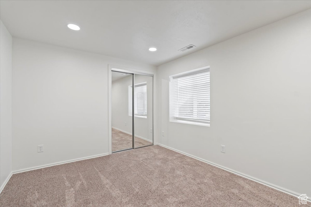 Unfurnished bedroom with light carpet, baseboards, recessed lighting, and a closet