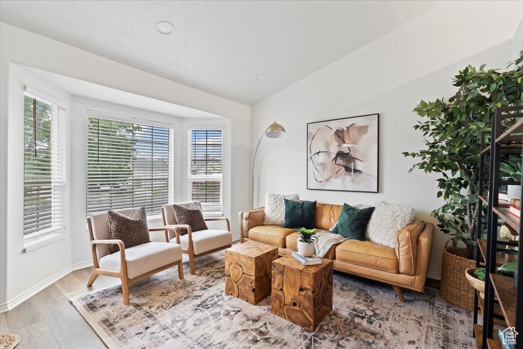 Living room with wood finished floors, lofted ceiling, baseboards, and recessed lighting