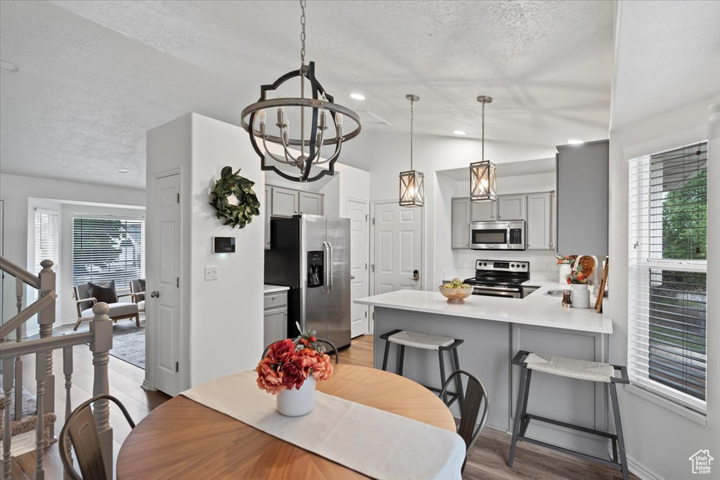 Dining area featuring a chandelier, a textured ceiling, wood finished floors, and baseboards