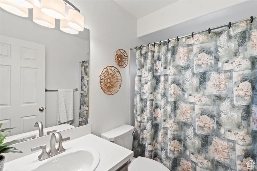 Bathroom featuring toilet, vanity, and a shower with shower curtain