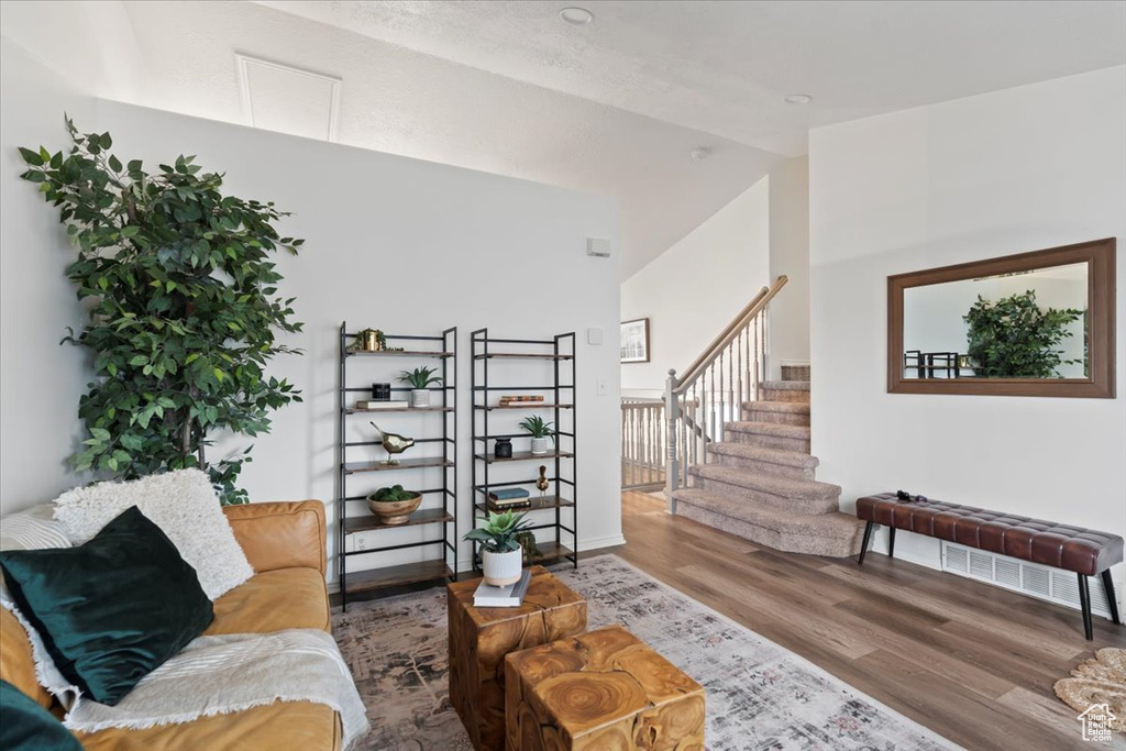 Living room with wood finished floors, lofted ceiling, and stairway