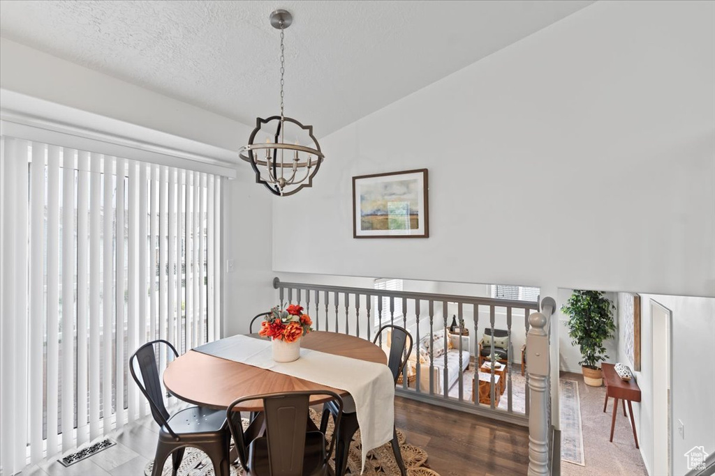 Dining room featuring a chandelier, vaulted ceiling, and a textured ceiling