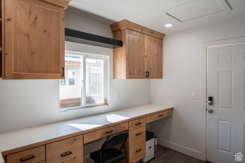 Unfurnished office with dark wood finished floors, recessed lighting, baseboards, and built in desk