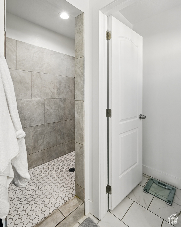 Bathroom with a tile shower, recessed lighting, baseboards, and marble look tile flooring