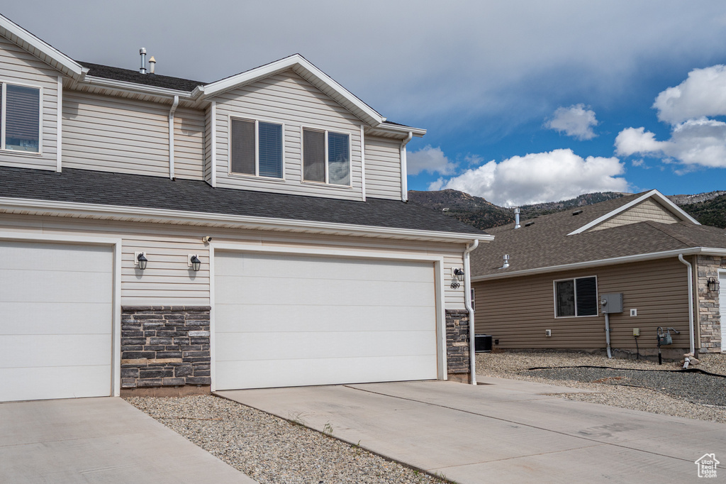 View of front facade featuring stone siding, a mountain view, concrete driveway, and a garage
