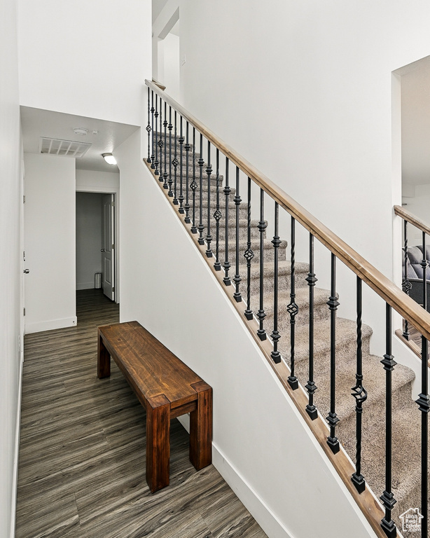 Stairs with baseboards, wood finished floors, and a high ceiling