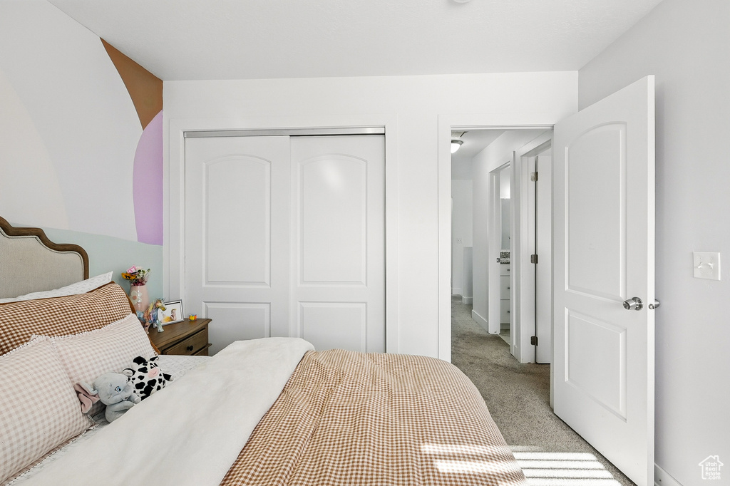 Bedroom featuring light carpet and a closet