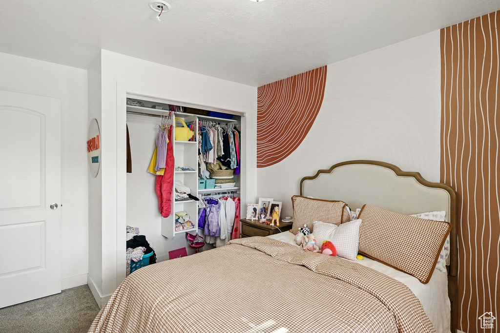 Carpeted bedroom featuring a closet and baseboards