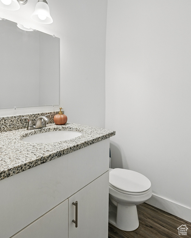 Bathroom featuring vanity, wood finished floors, toilet, and baseboards