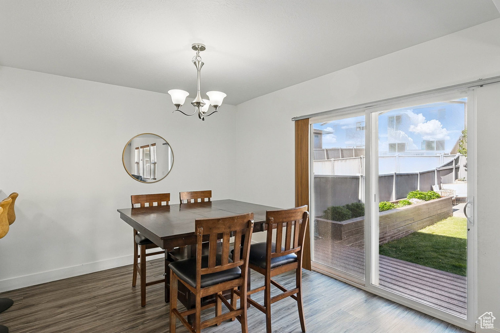 Dining space with a chandelier, wood finished floors, and baseboards