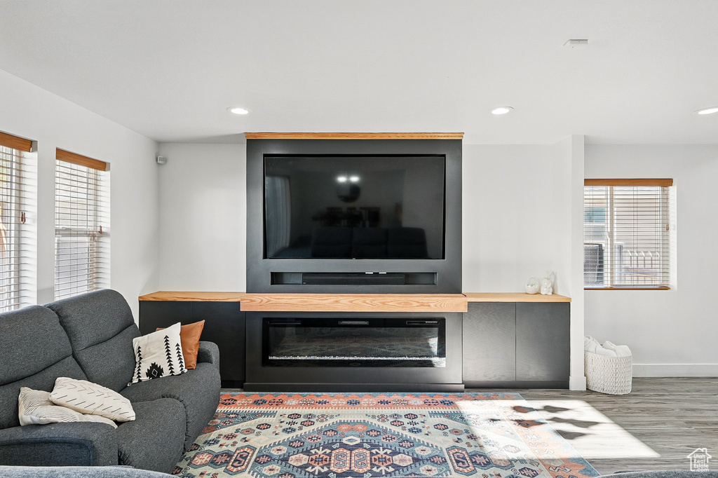 Living area featuring healthy amount of natural light, wood finished floors, baseboards, recessed lighting, and a large fireplace