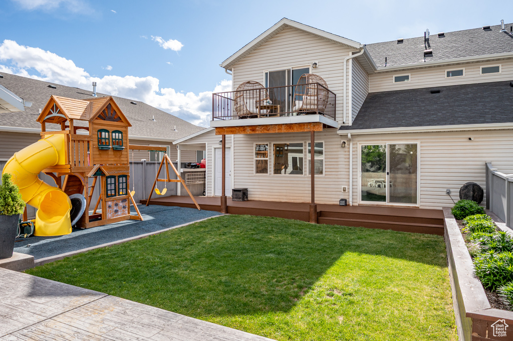 Rear view of house with a balcony, a playground, and roof with shingles