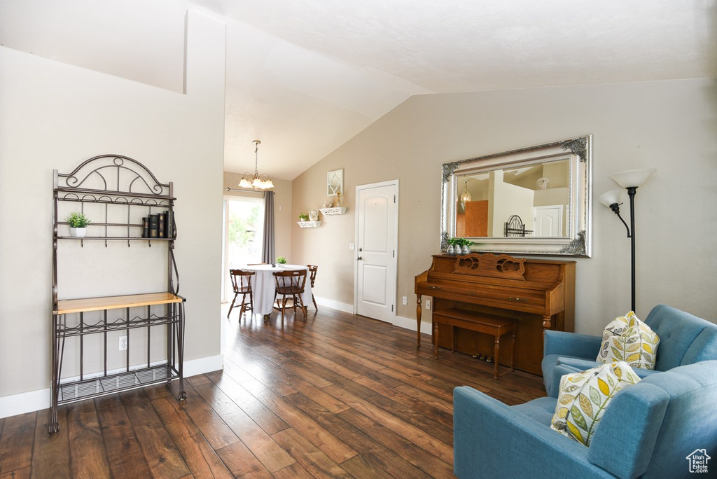 Living area with a chandelier, vaulted ceiling, hardwood / wood-style flooring, and baseboards