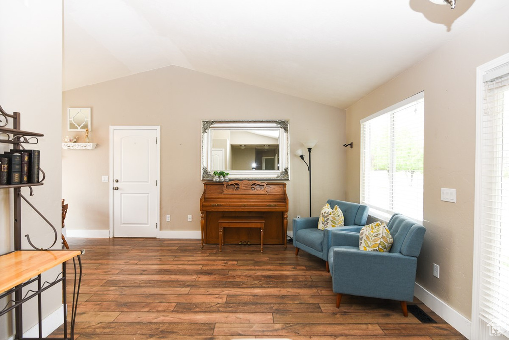 Living area with vaulted ceiling, wood finished floors, and baseboards